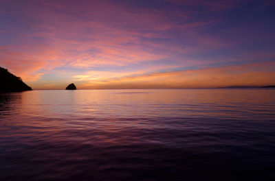 Scenic view of sea against dramatic sky during sunset