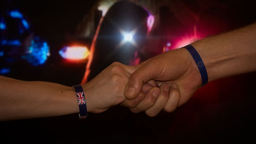 Close-up of man holding hands at night
