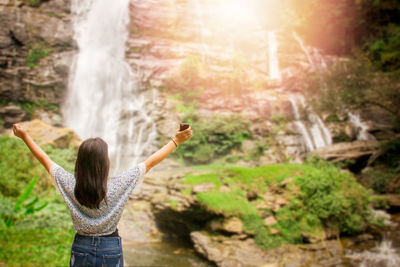 Rear view of woman standing against waterfall