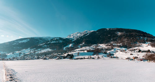 Scenic view of village by mountains against blue sky