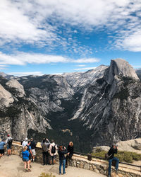 People walking on mountain road against sky