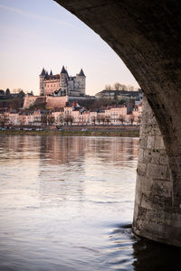 Arch bridge over river against buildings in city