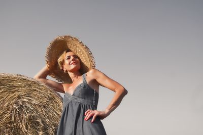 Low angle view of woman wearing hat while standing against sky
