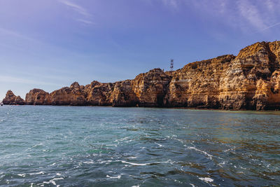 Scenic view of sea and rocks against blue sky