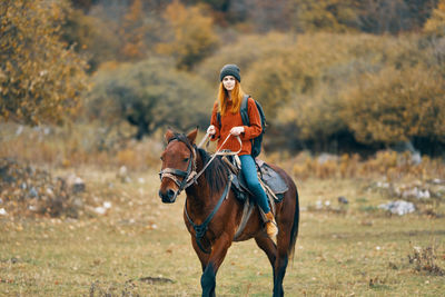 Young woman riding horse on field