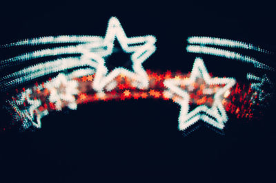 Low angle view of illuminated lighting equipment against black background