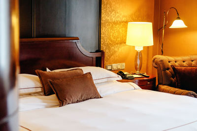 Pillows on bed in illuminated bedroom at home