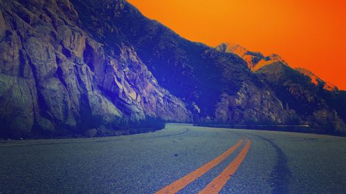 Close-up of road by mountain against sky during sunset