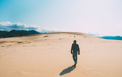 Rear view of man on desert against sky