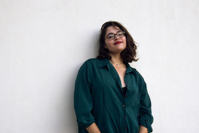 Portrait of smiling young woman standing against wall