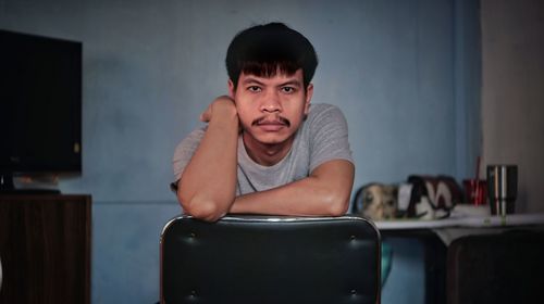 Portrait of young man sitting on table at home
