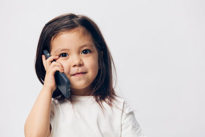 Portrait of young woman using mobile phone against white background