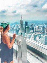 Woman standing by modern buildings against sky