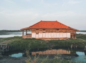 House by lake against sky