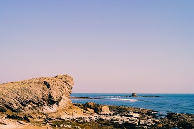 Scenic view of sea and rocks against clear sky