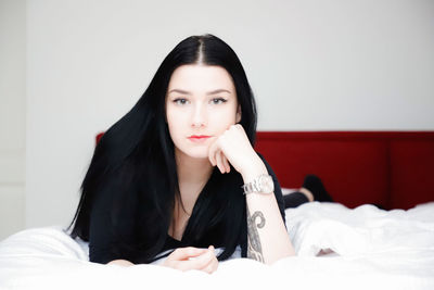 Portrait of beautiful young woman sitting on bed