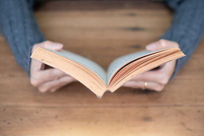 Midsection of woman reading book heart shape on table