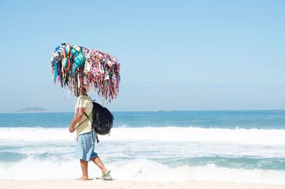 Side view of man selling bikinis on shore at beach