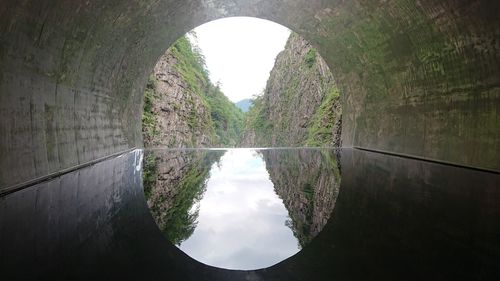 Arch bridge over canal amidst trees against sky