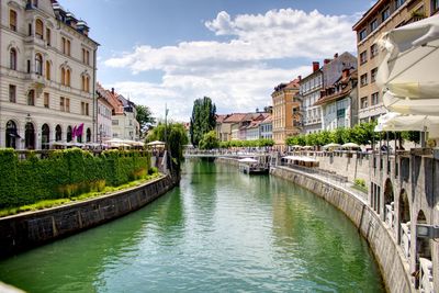 Canal amidst buildings in city against sky