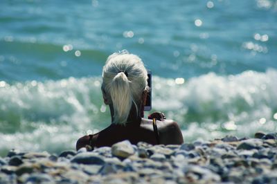 Rear view of woman sitting in sea