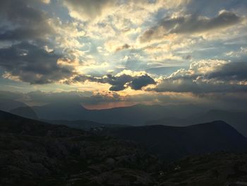 Scenic view of mountains against cloudy sky during sunset