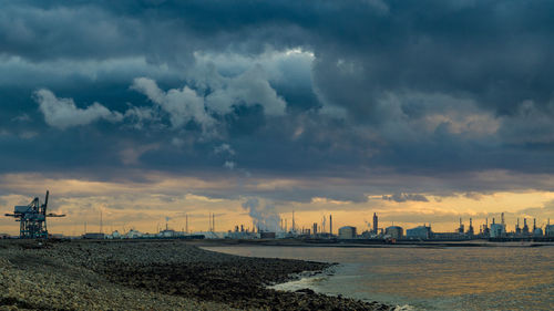 City at waterfront against cloudy sky