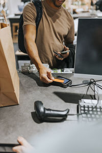 Midsection of mature man scanning credit card on reader at checkout in electronics store