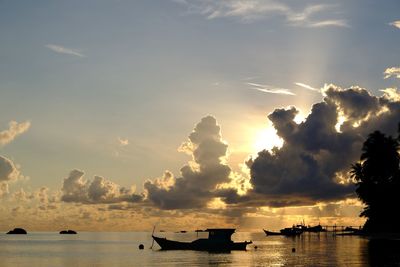 Silhouette boats in sea against sky during sunset