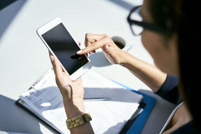 Close-up of businesswoman using cell phone at desk in office