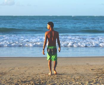 Rear view of man walking on sand at beach