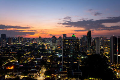 Illuminated cityscape against sky during sunset