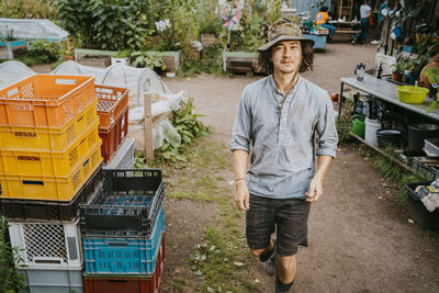 Portrait of young male volunteer walking by crates in farm