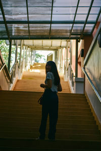 Full length of young woman standing on staircase in building