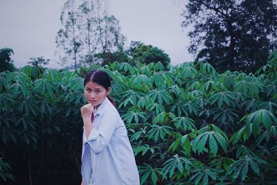 Young woman holding while standing by plants