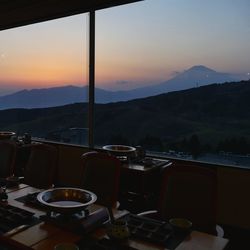 Empty chairs and tables against sky during sunset