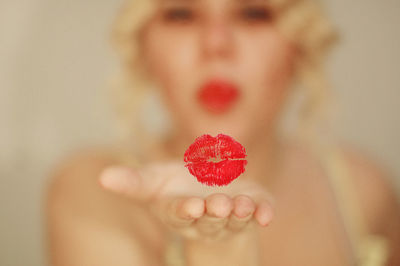 Digital composite image of woman blowing lipstick kiss in mid-air