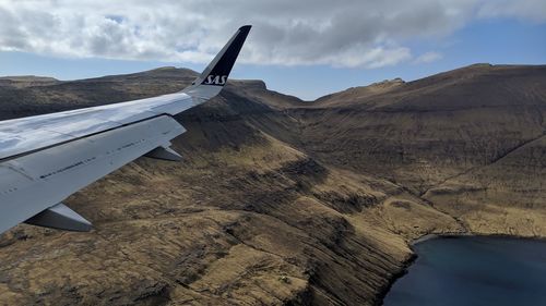 Airplane flying over landscape against sky