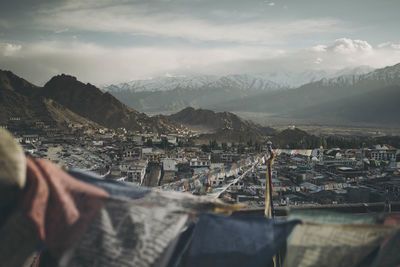 High angle view of buildings and mountains against cloudy sky