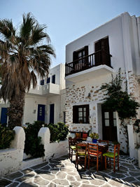 House and palm trees by building against sky