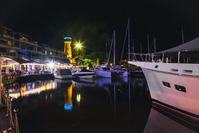 Boats moored in harbor at night