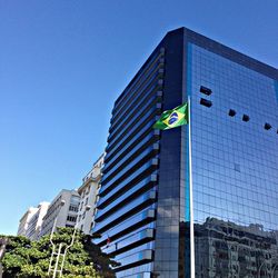 Low angle view of brazilian flag and buildings against clear sky