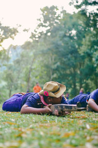 Rear view of friends lying down on land against trees