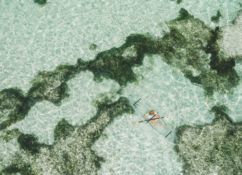 High angle view of mid adult woman canoeing in sea against sky