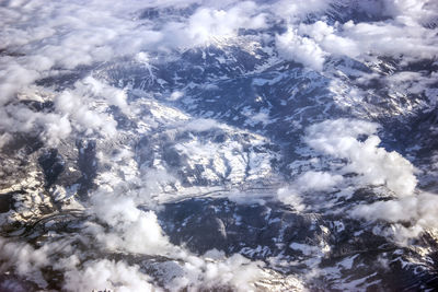Aerial view of mountains against clouds during winter