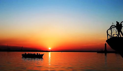 Silhouette boat in sea against sky during sunset