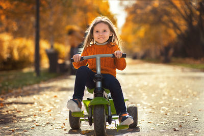 Portrait of smiling girl riding bicycle in park during autumn