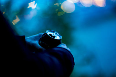 Close-up of hand holding blue light against blurred background