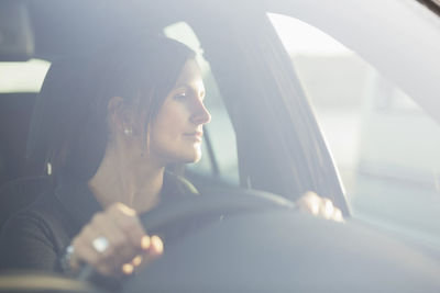 Young businesswoman looking through window while driving car