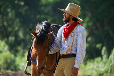 Man wearing costume standing by horse against trees